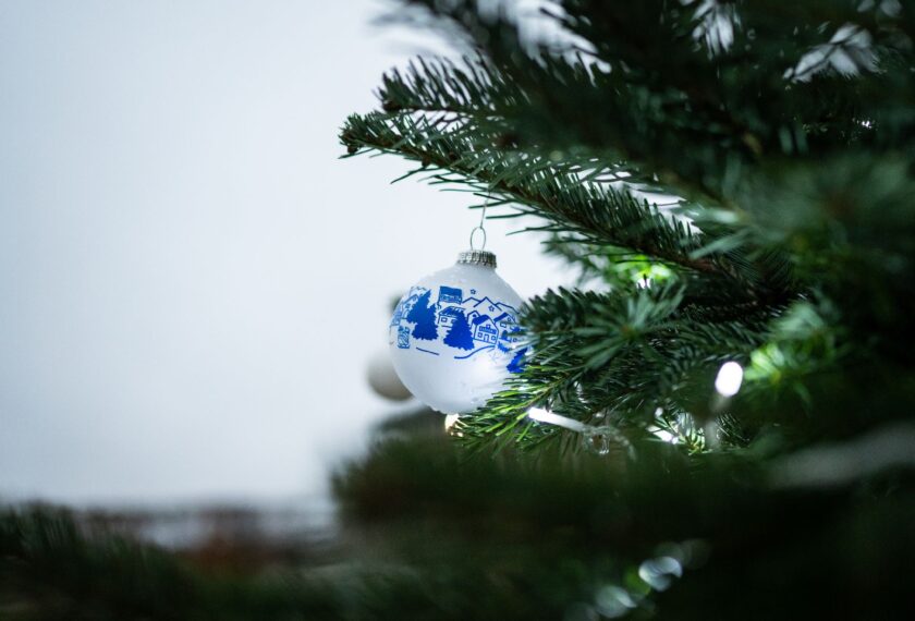 Weihnachtsbaum mit einer weißen Christbaumkugel, die eine blau-weiße Illustration einer Stadtlandschaft zeigt.