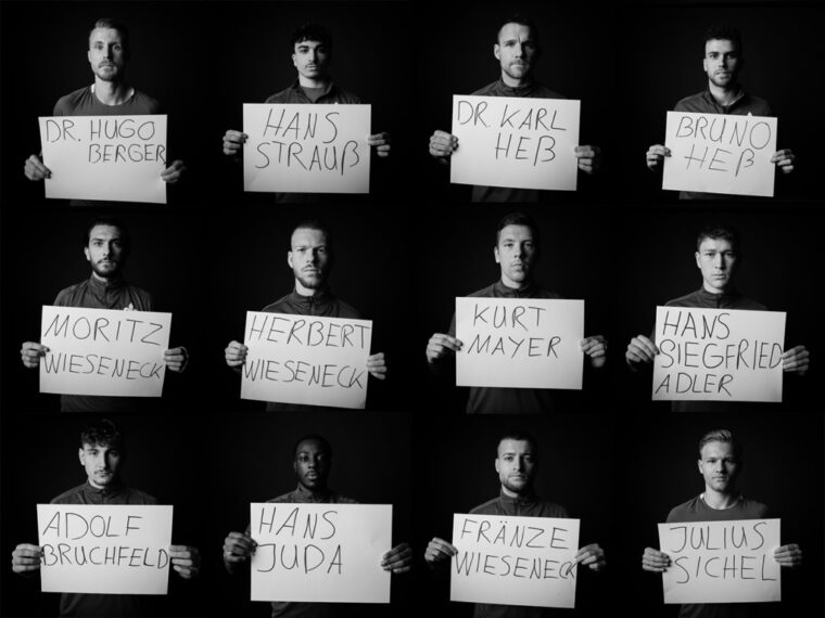 Zwölf Personen halten jeweils ein Schild mit den Namen von Menschen vor sich. Die Namen auf den Schilden sind: Dr. Hugo Berger, Hans Strauß, Dr. Karl Heb, Bruno Heb, Moritz Wieseneck, Herbert Wieseneck, Kurt Mayer, Hans Siegfried Adler, Adolf Bruchfeld, Hans Juda, Fränze Wieseneck und Julius Sichel. Die Personen stehen vor einem schwarzen Hintergrund und sind in schwarz-weiß dargestellt.