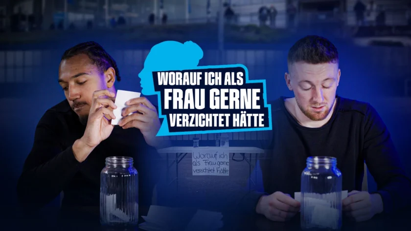 Zwei Männer sitzen an einem Tisch und schreiben auf Zettel, was sie als Frau gerne verzichten würden. Im Hintergrund ist ein Stadion zu sehen.