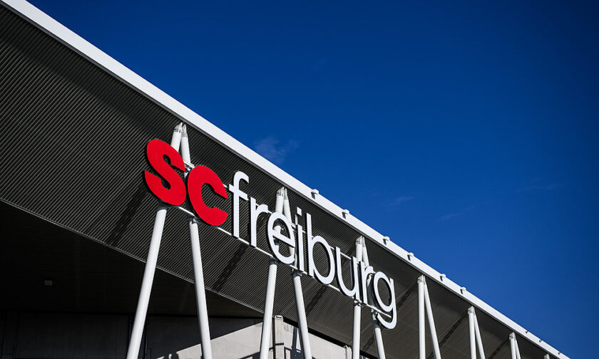 SC Freiburg Stadion mit dem Schriftzug SC Freiburg an der Fassade unter blauem Himmel.