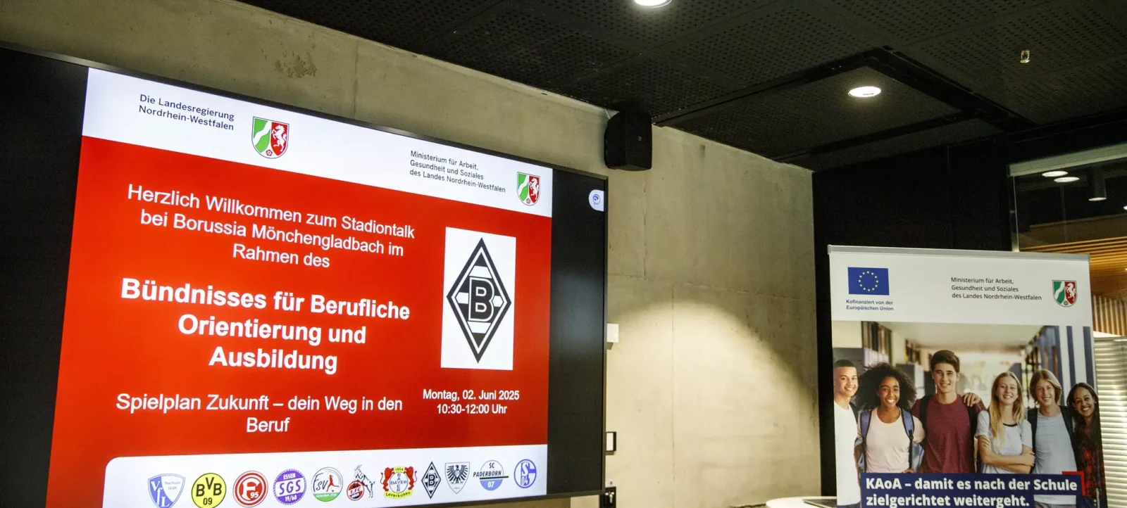 Ein Plakat mit der Einladung zum Stadiontalk bei Borussia Mönchengladbach im Rahmen des Bündnisses für Berufliche Orientierung und Ausbildung. Das Plakat zeigt das Logo des Vereins und Informationen zum Termin sowie die teilnehmenden Vereine. Im Hintergrund ist ein weiteres Plakat mit dem Titel "KAoA – damit es nach der Schule zielgerichtet weitergeht" zu sehen.