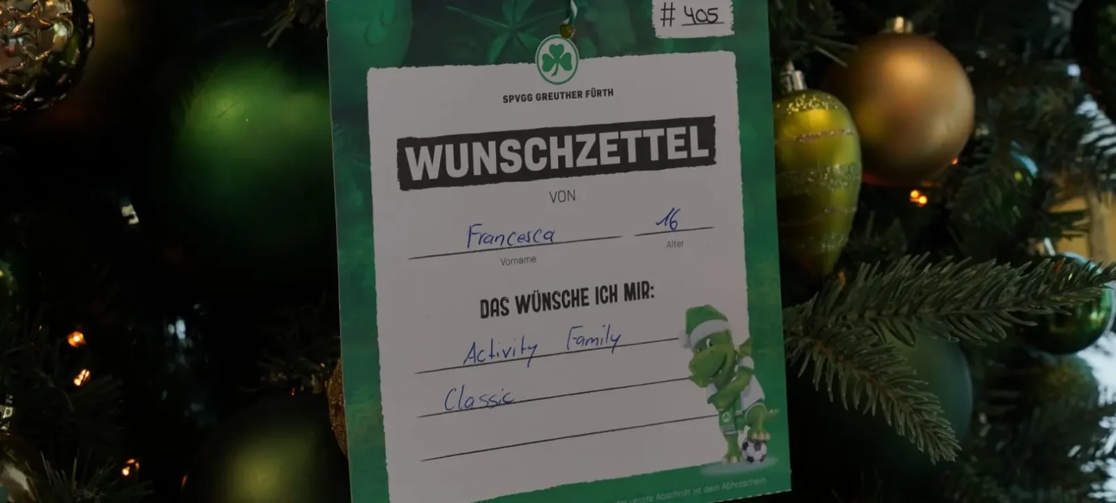 Ein Wunschzettel der SPVGG Greuther Fürth hängt an einem geschmückten Weihnachtsbaum. Der Wunschzettel ist von Francesca, 16 Jahre alt, und enthält die Wünsche "Activity Family" und "Classic".