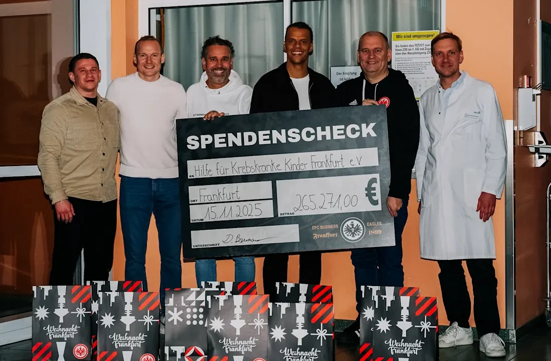 Eine Gruppe von fünf Personen hält einen großen Scheck über 265.271,00 Euro für den Verein "Hilfe für krebskranke Kinder Frankfurt e.V." Sie stehen vor mehreren Geschenkboxen mit dem Aufdruck "Weihnachten Frankfurt". Die Personen lächeln und wirken zufrieden.